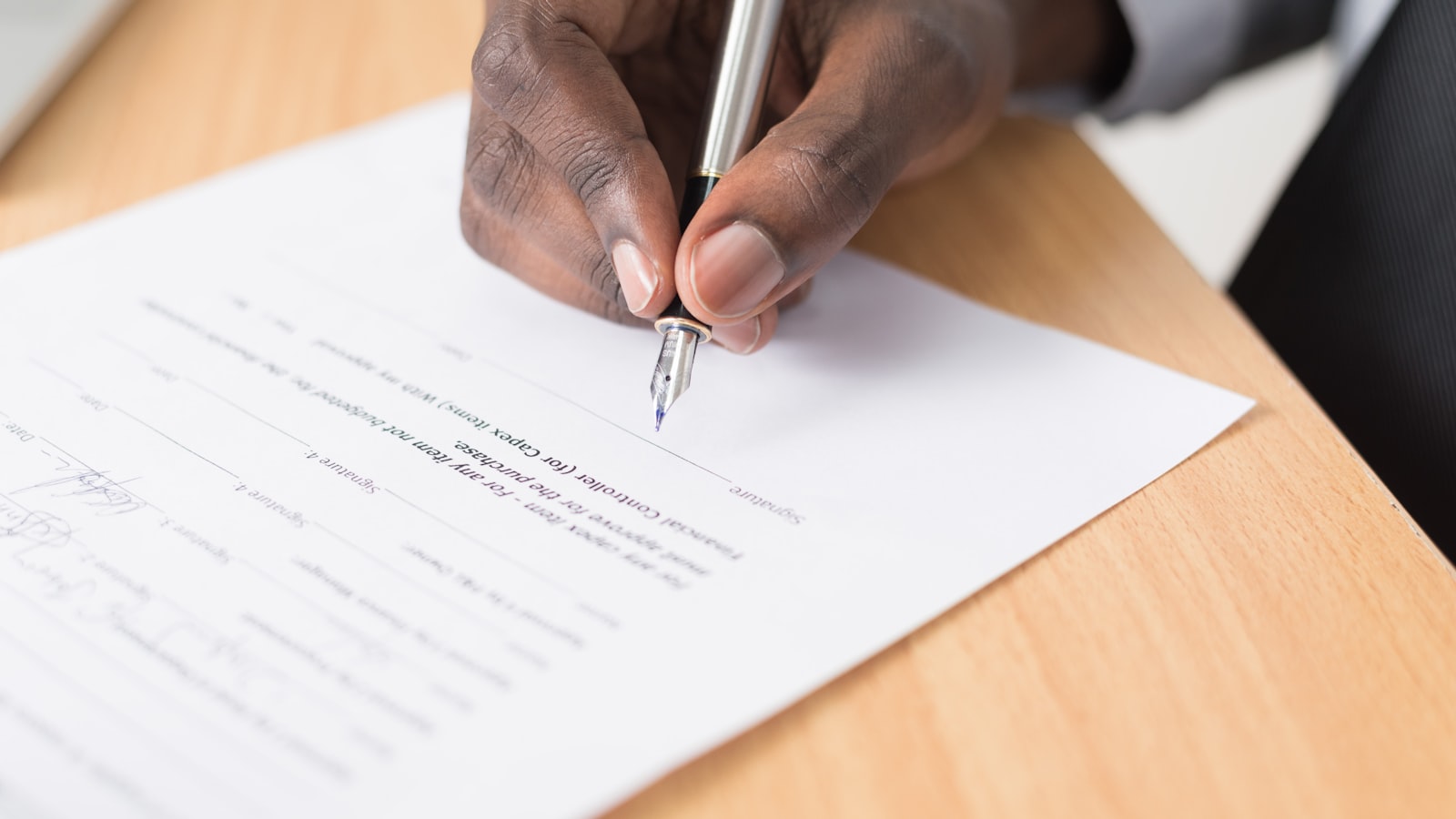 A person writing on a document, representing verifiable parental consent workflows